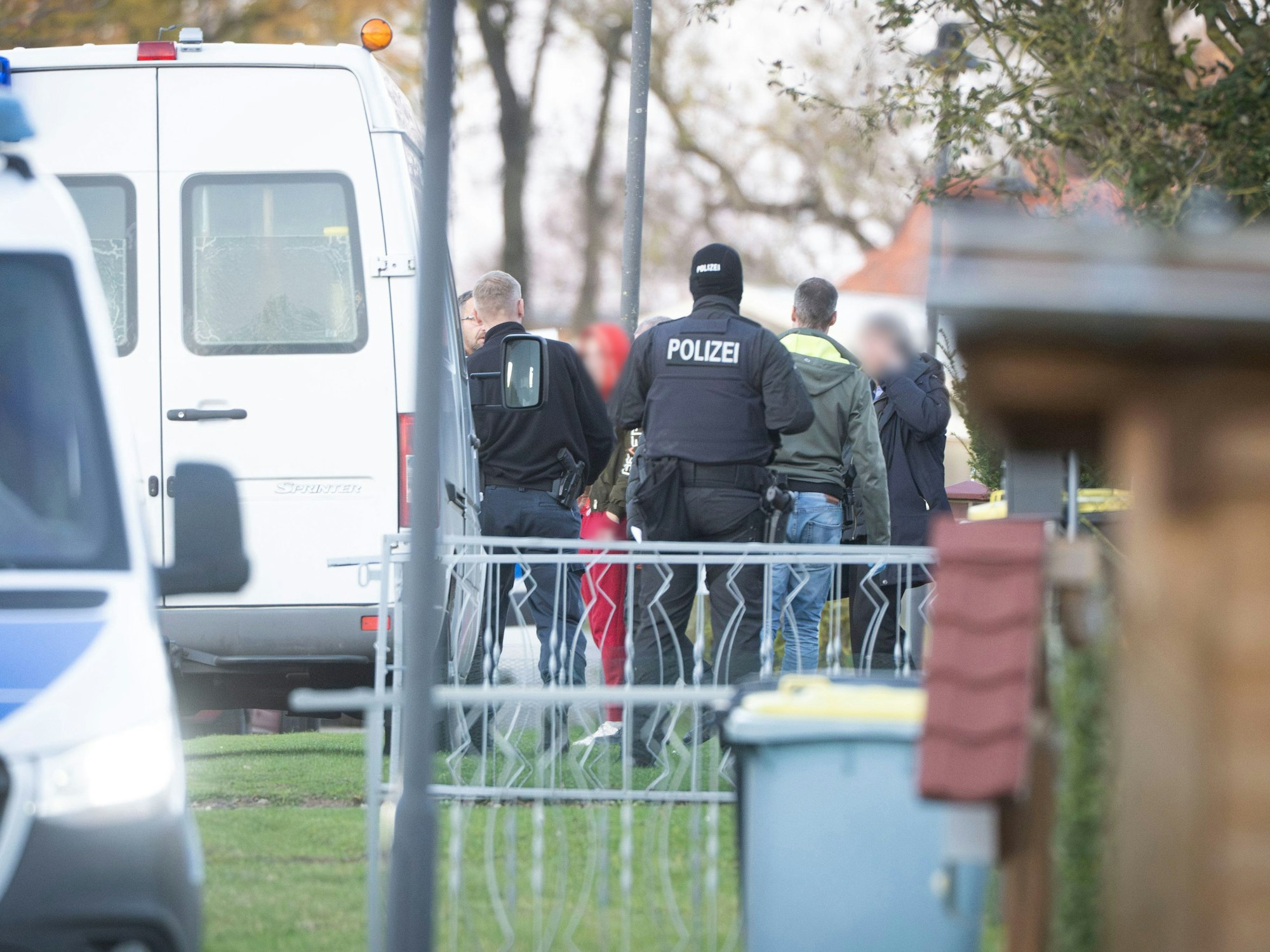 Eine tatverdächtige Frau (Mitte l) verlässt in Begleitung von Polizeibeamten ihr Wohnhaus.