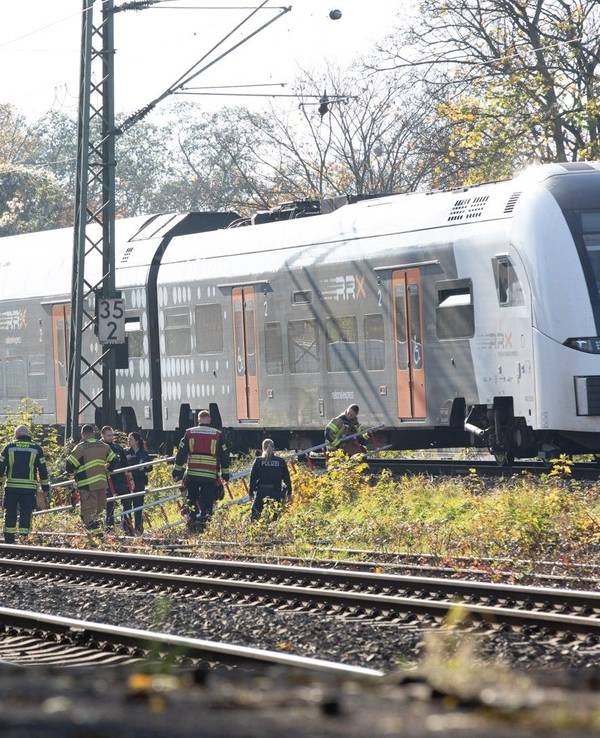 Einsatzkräfte tragen Leitern zu einem Regionalzug. Die Feuerwehr hat in Neuss einen Zug mit rund 180 Fahrgästen, der aufgrund eines Oberleitungsschadens liegen geblieben sein soll, evakuiert.