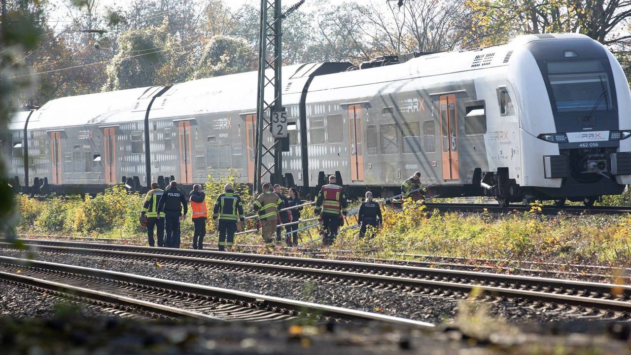 Einsatzkräfte tragen Leitern zu einem Regionalzug. Die Feuerwehr hat in Neuss einen Zug mit rund 180 Fahrgästen, der aufgrund eines Oberleitungsschadens liegen geblieben sein soll, evakuiert.