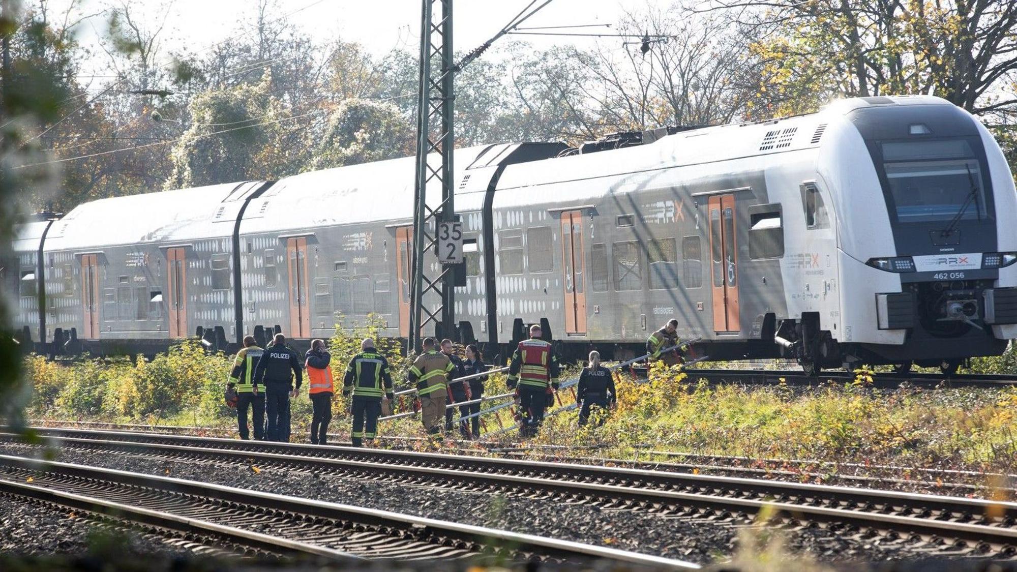 Einsatzkräfte tragen Leitern zu einem Regionalzug. Die Feuerwehr hat in Neuss einen Zug mit rund 180 Fahrgästen, der aufgrund eines Oberleitungsschadens liegen geblieben sein soll, evakuiert.