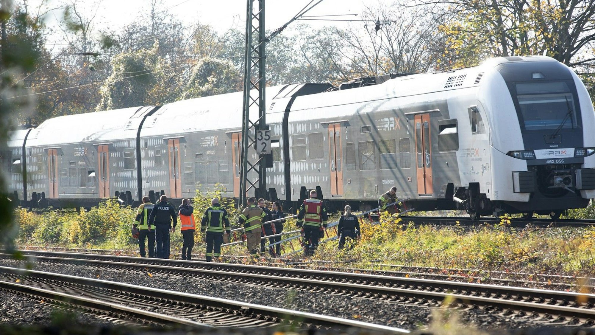 Einsatzkräfte tragen Leitern zu einem Regionalzug. Die Feuerwehr hat in Neuss einen Zug mit rund 180 Fahrgästen, der aufgrund eines Oberleitungsschadens liegen geblieben sein soll, evakuiert.