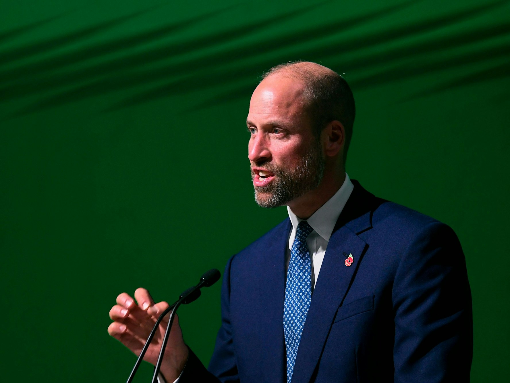 Ein Mann, der einen Anzug trägt, spricht in ein Mikrofon.