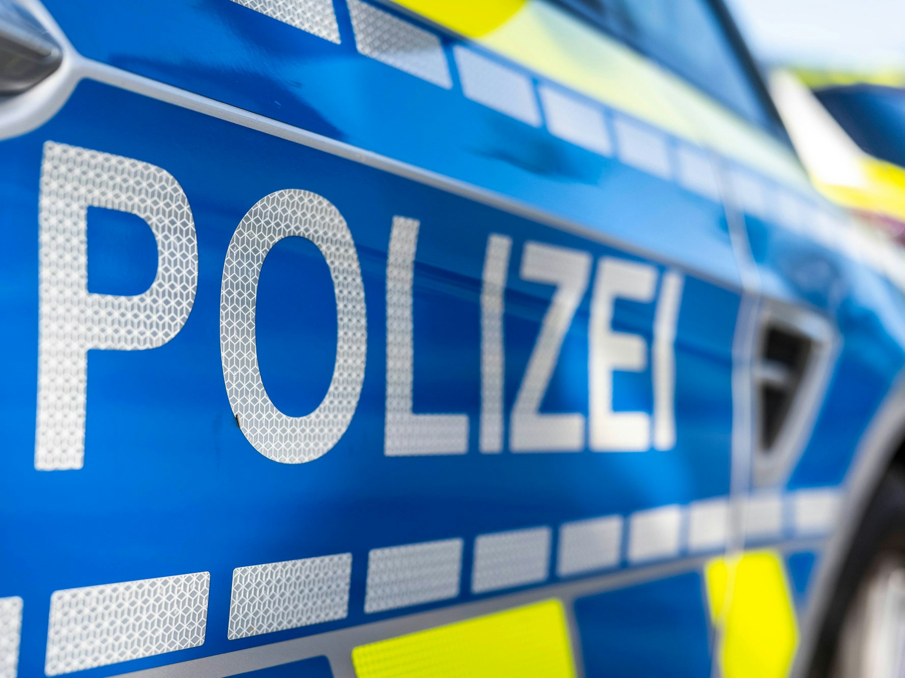 An der Tür von einem Streifenwagen steht der Schriftzug „Polizei“.