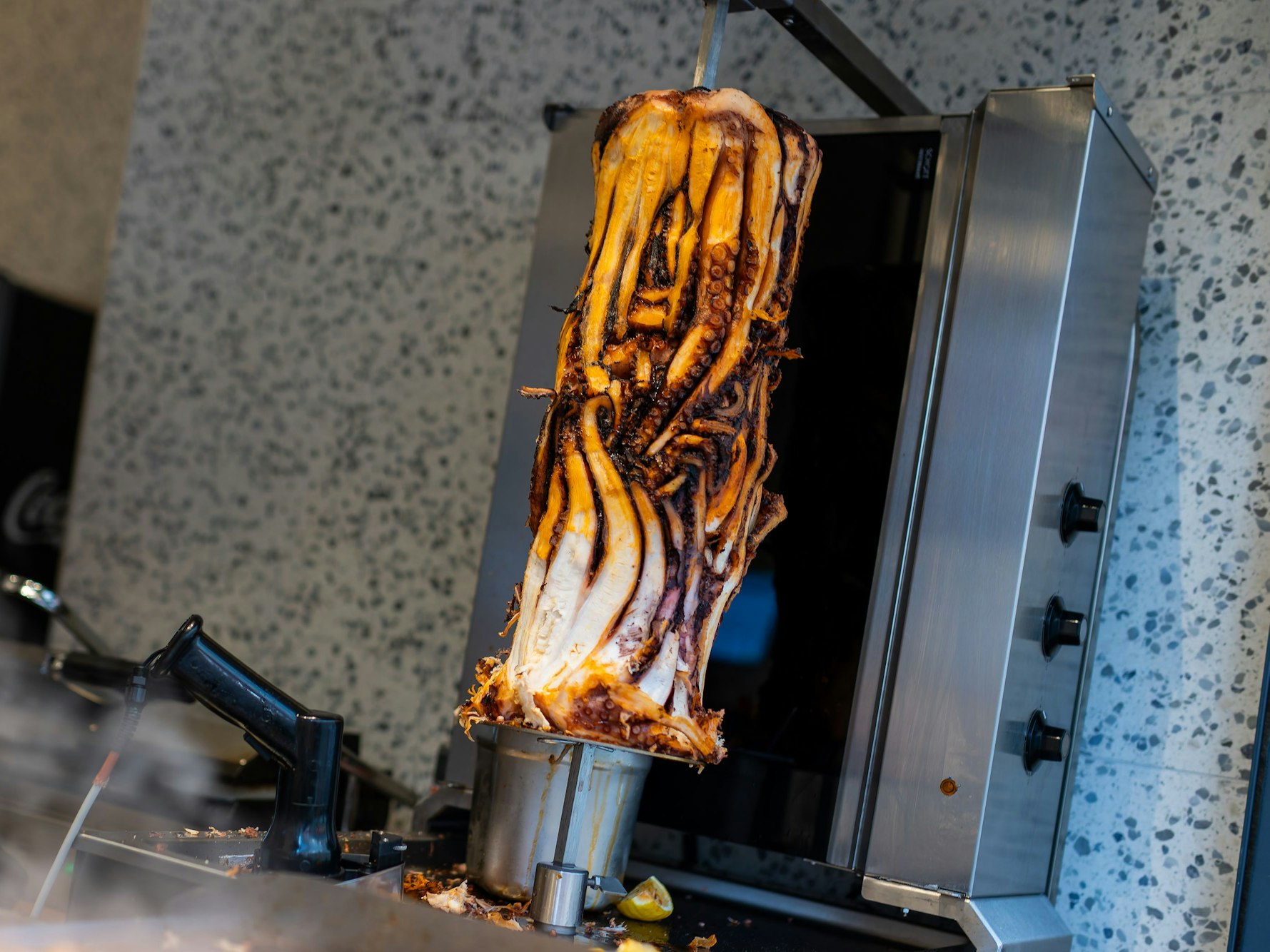 PRODUKTION - 07.11.2025, Baden-Württemberg, Karlsruhe: Ein Calamari-Kebabspiess hängt im Restaurant «Pescobar». Nach der ersten Filiale in London hat ein rumänischer Meeresfrüchte-Anbieter nun seine zweite Filiale mit Calamari-Kebab in Karlsruhe eröffnet. (zu dpa: «Neuer Döner-Hype? Tentakel am Spieß sorgt für Wirbel») Foto: Philipp von Ditfurth/dpa +++ dpa-Bildfunk +++