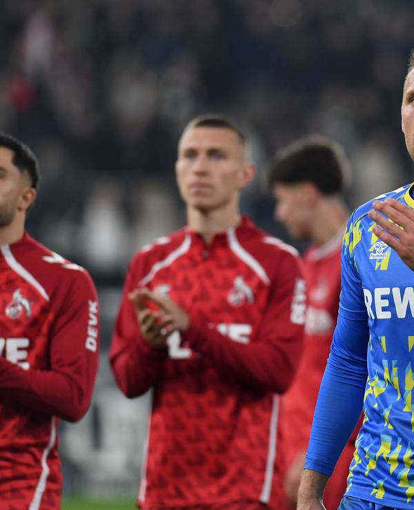 Marvin Schwäbe und weitere Spieler des 1. FC Köln im Hintergrund bedanken sich bei den Fans im Stadion.