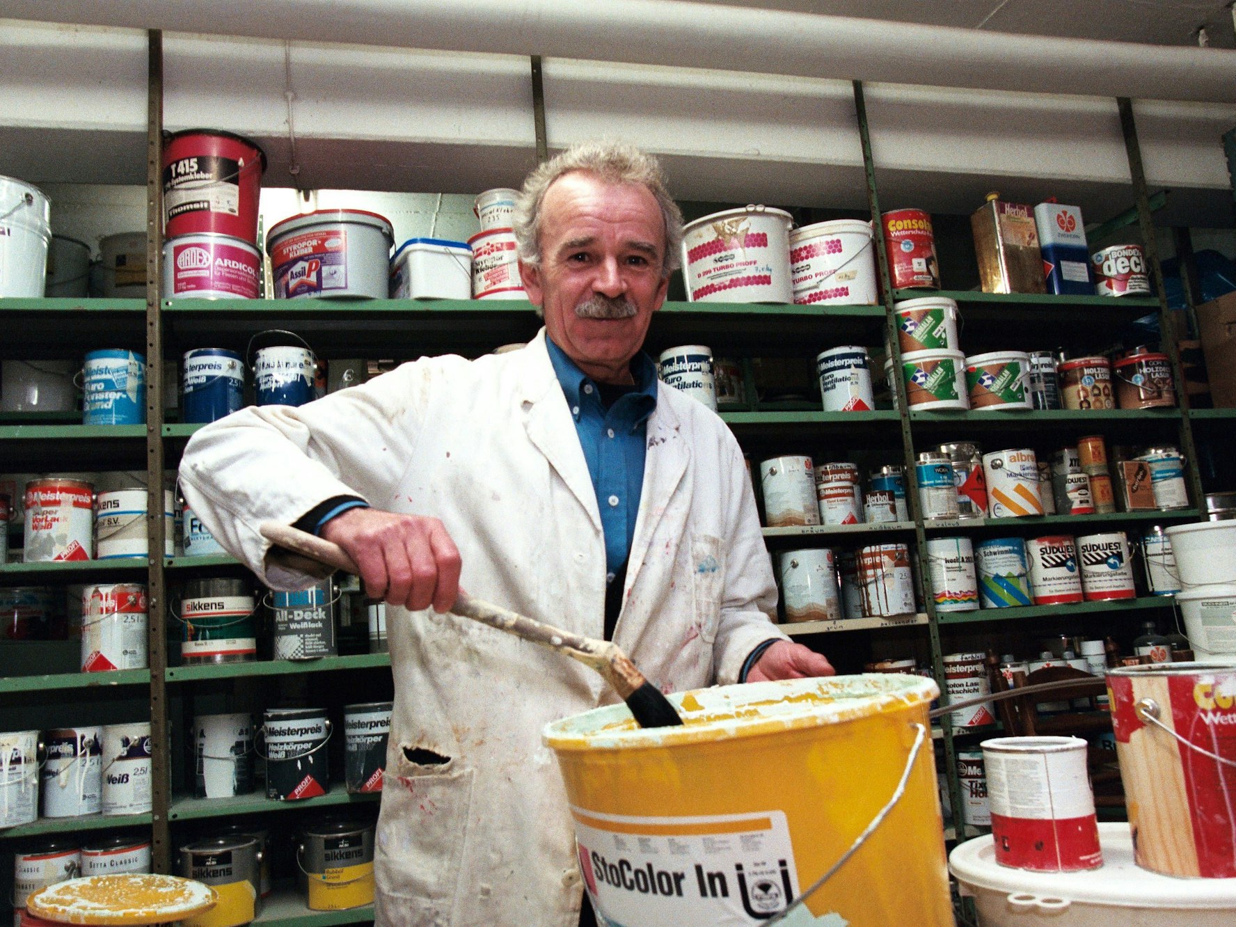 Heinz Simmet mit Farbe und Pinsel in seinem Malerbetrieb.