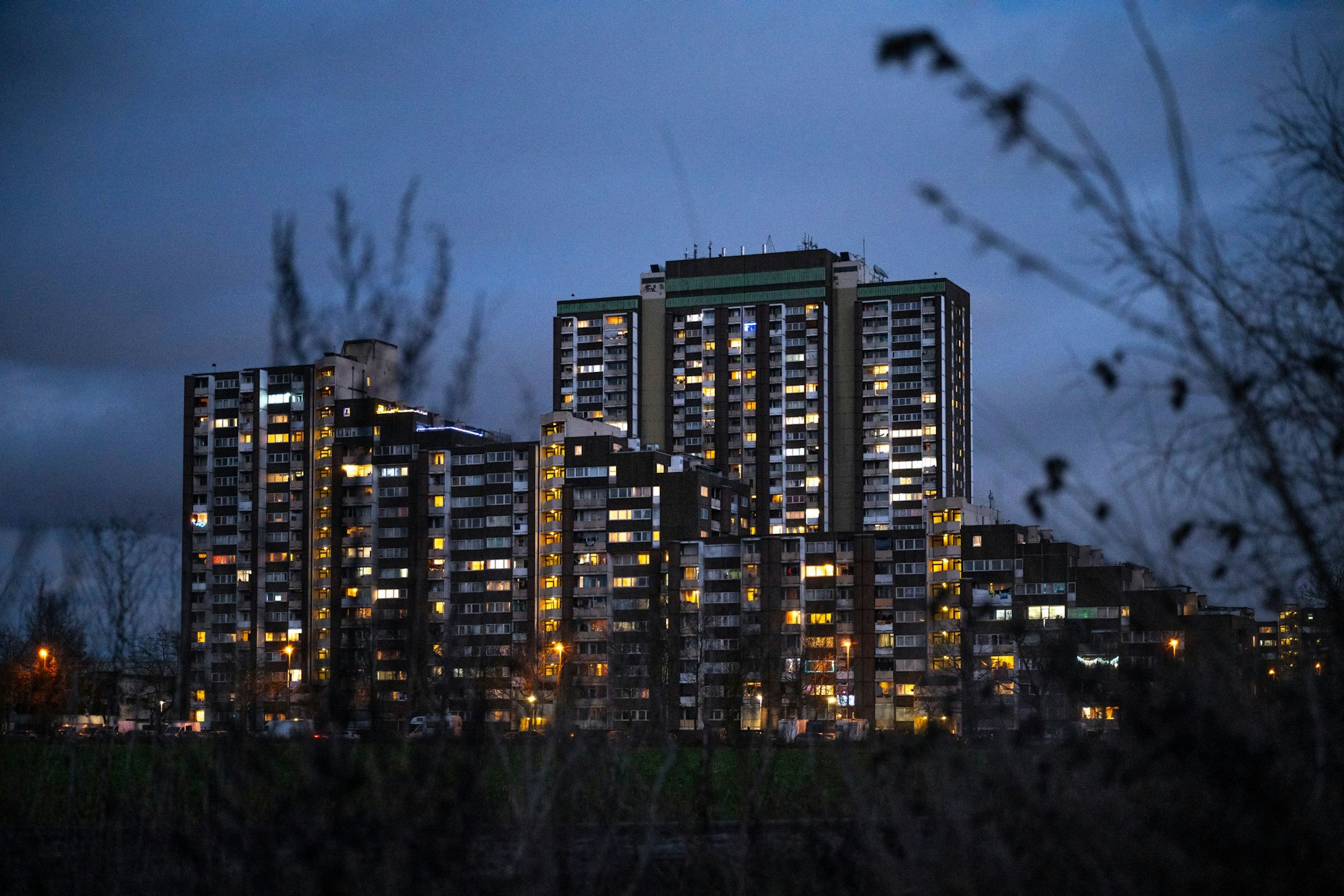 Die Hochhäuser am Kölnberg in Meschenich sind in der Abenddämmerung weihnachtlich beleuchtet.