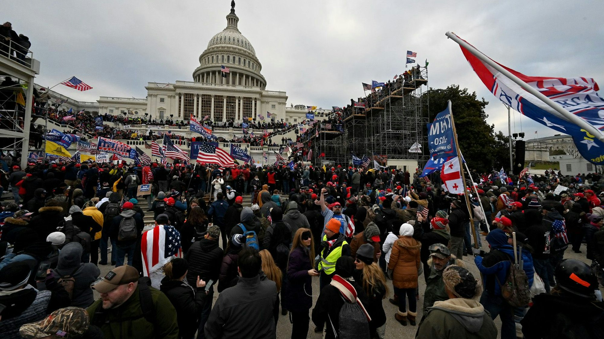 Menschen stehen vor einem monumentalen Gebäude. Einige schwenken Flaggen.