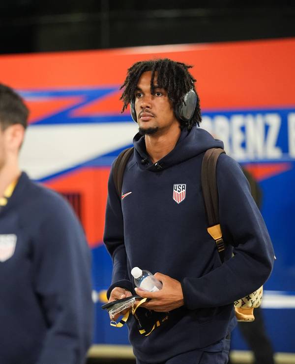 Damion Downs hat Kopfhörer an und läuft mit einem Rucksack und einer Flasche in der Hand durch die Katakomben eines Stadions.
