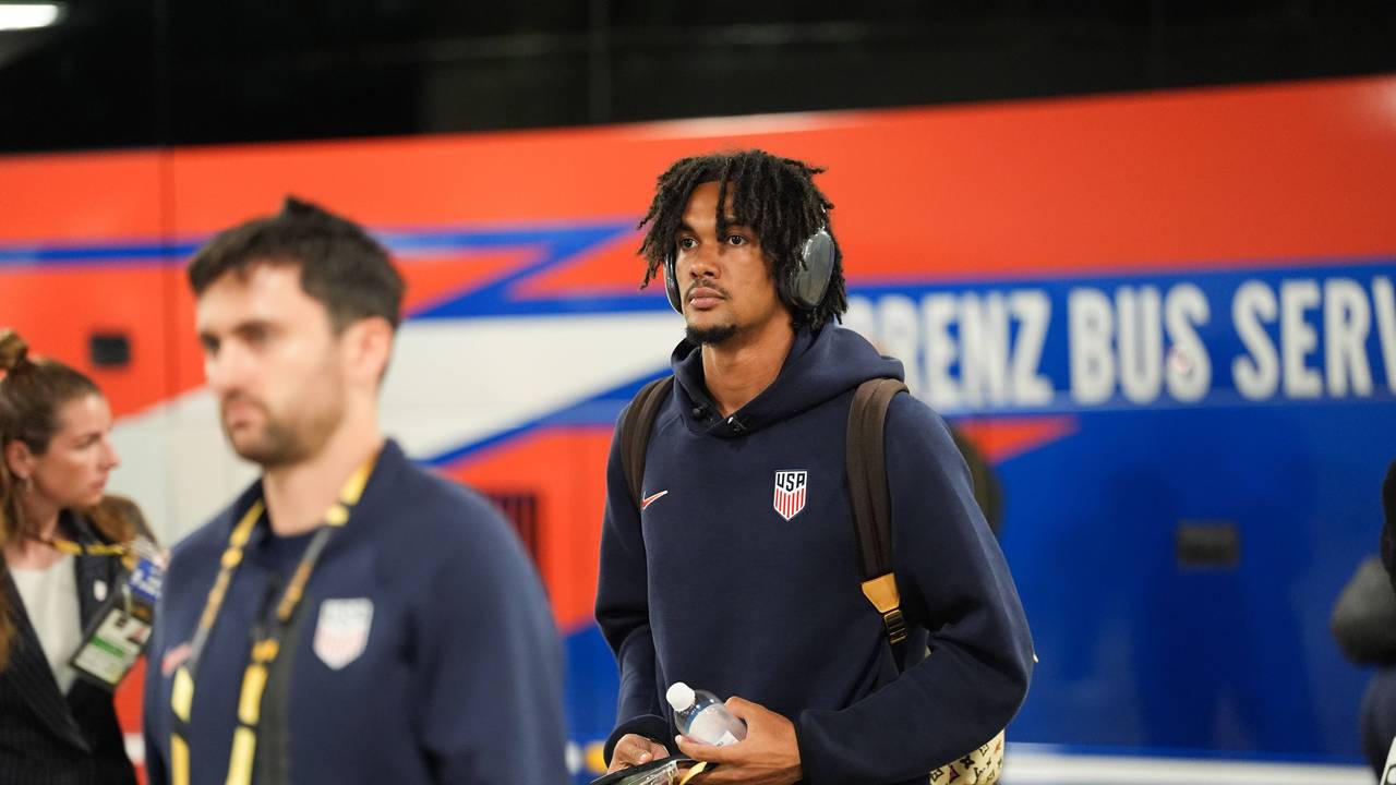 Damion Downs hat Kopfhörer an und läuft mit einem Rucksack und einer Flasche in der Hand durch die Katakomben eines Stadions.