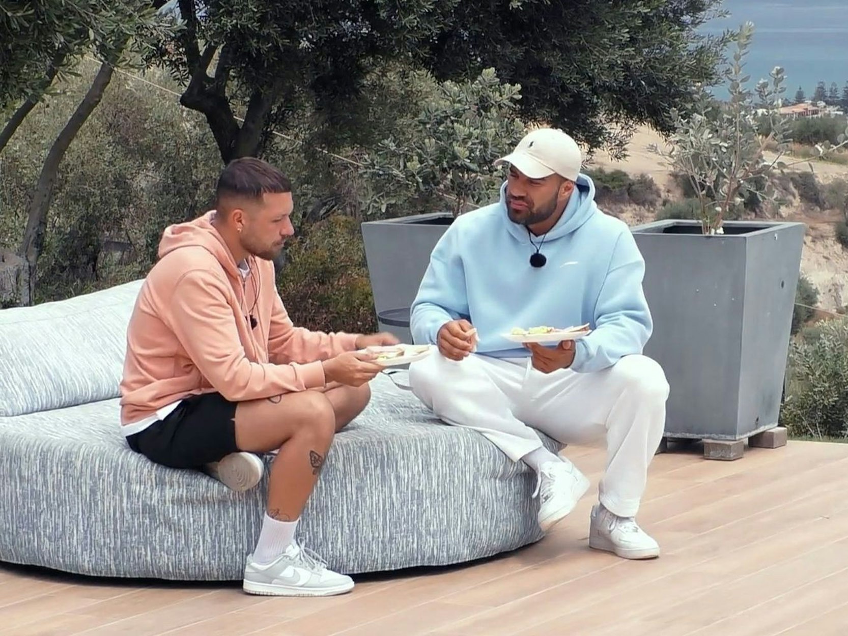 Zwei Männer sitzen auf einem Sitzsack und reden miteinander.