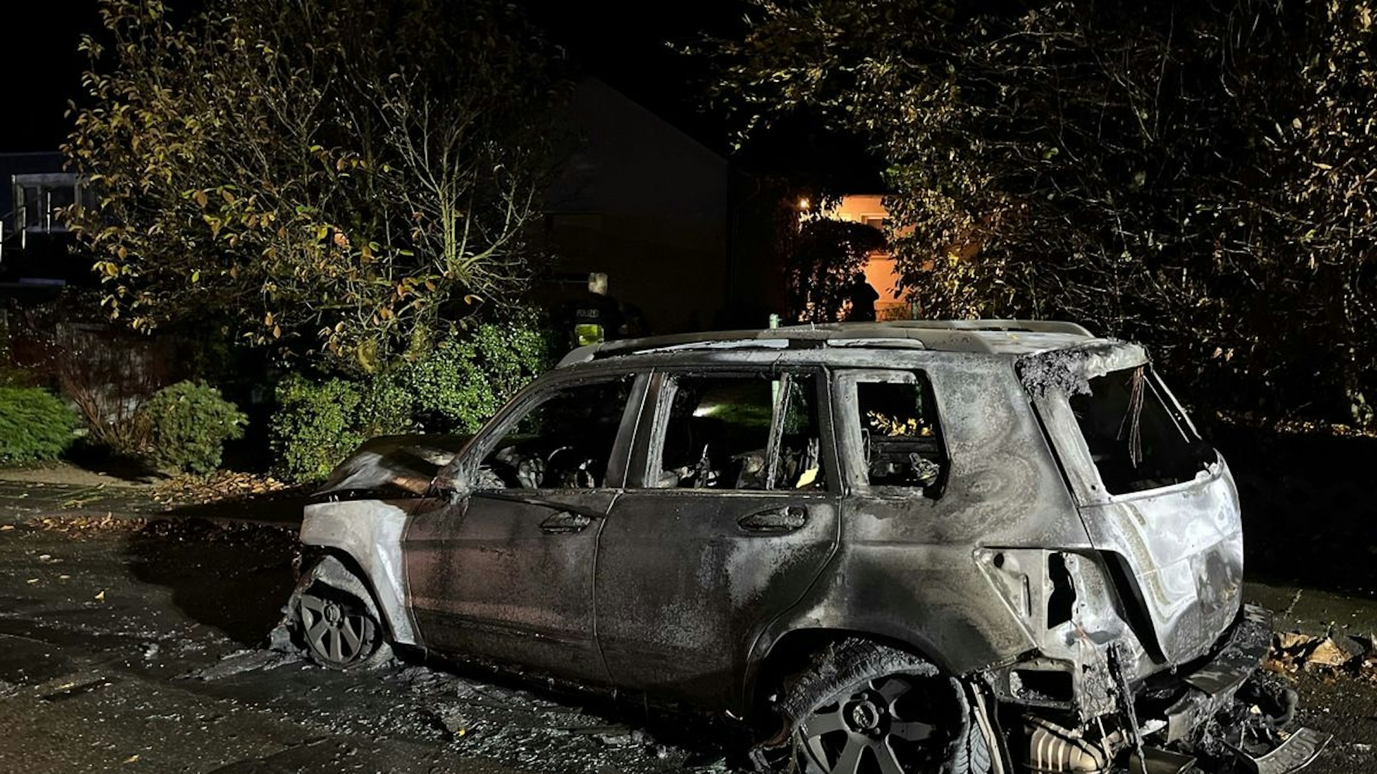 Ein ausgebranntes Auto steht am Straßenrand.