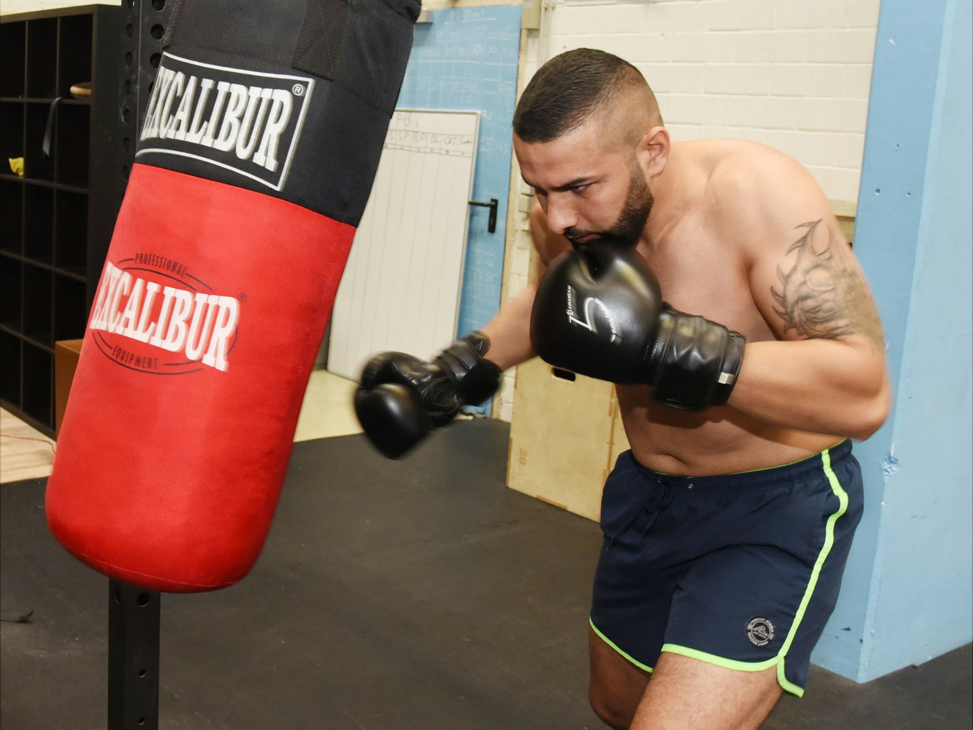 Ein Mann schlägt mit Boxhandschuhen auf einen Box-Sack ein.