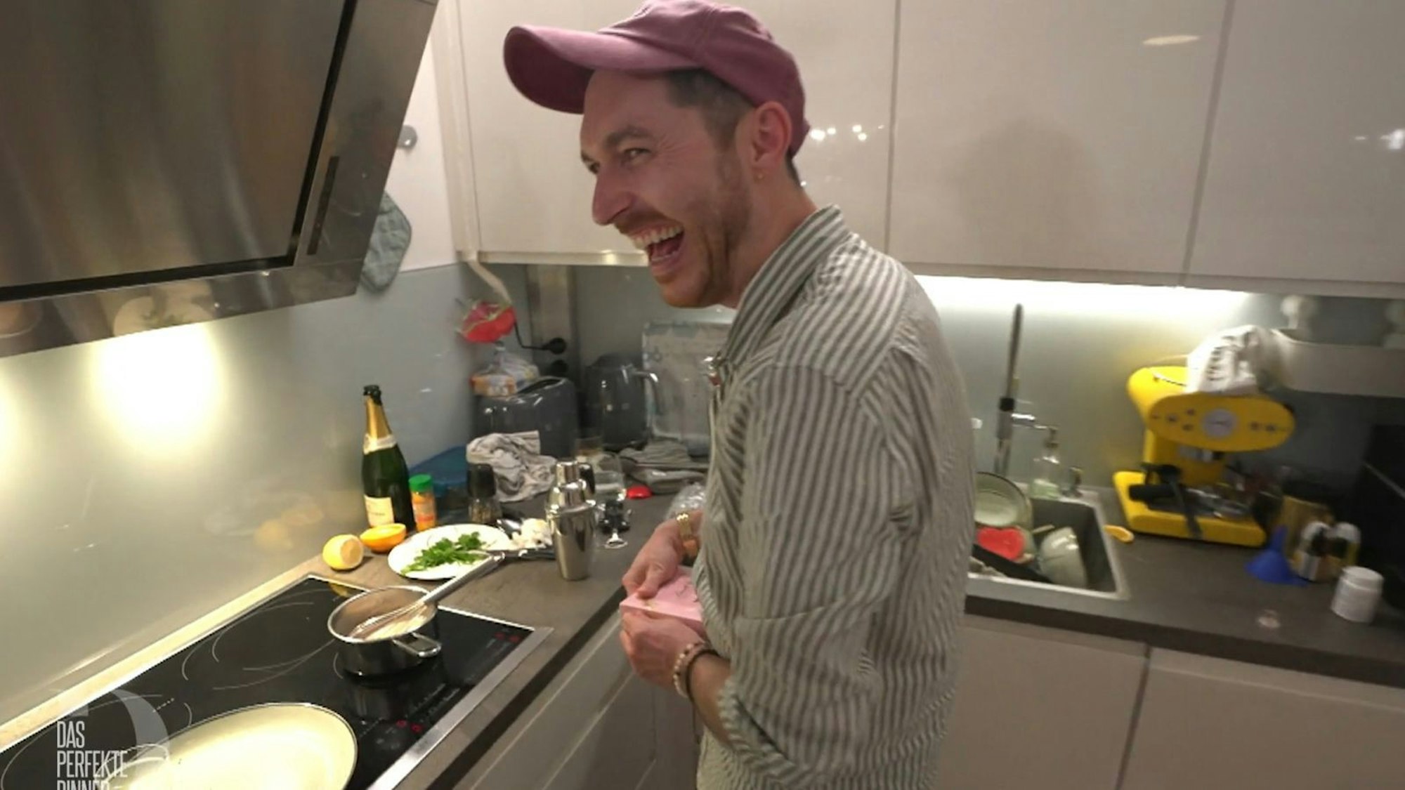 Ein Mann steht lachend in einer Küche.