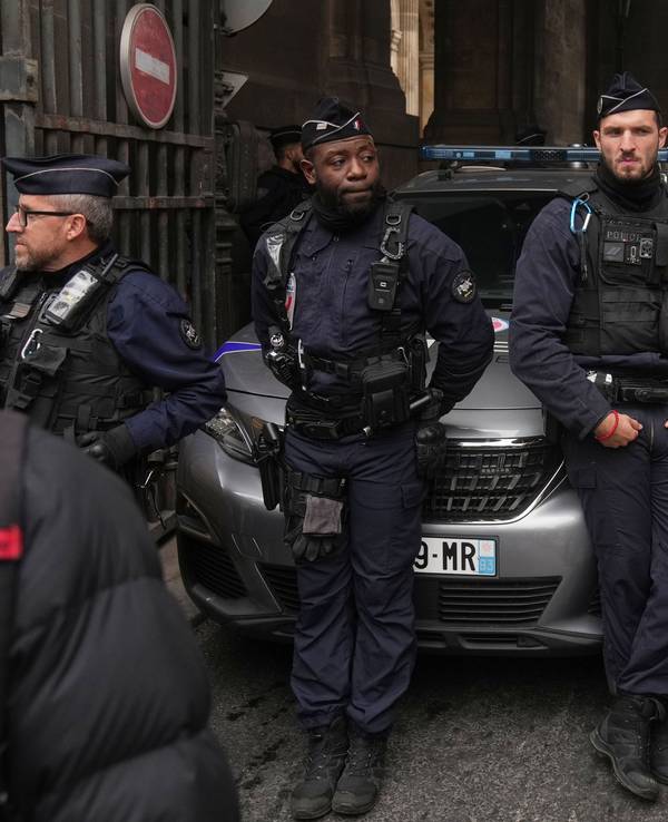Pedro Elias Garzon Delvaux, rechts, geht an Polizisten vorbei, die einen Eingang zum Louvre blockieren, nachdem Diebe bei Tageslicht einen Überfall auf französische Kronjuwelen verübt haben. Nachdem das Foto eines auffällig gekleideten jungen Mannes im 40er-Jahre-Look vor dem Pariser Louvre nach dem Museums-Einbruch viral ging, ist das Rätsel um seine Identität gelöst.
