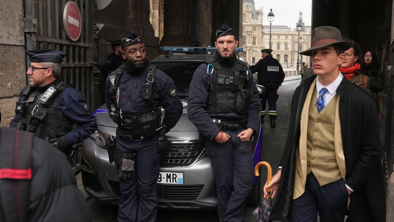 Pedro Elias Garzon Delvaux, rechts, geht an Polizisten vorbei, die einen Eingang zum Louvre blockieren, nachdem Diebe bei Tageslicht einen Überfall auf französische Kronjuwelen verübt haben. Nachdem das Foto eines auffällig gekleideten jungen Mannes im 40er-Jahre-Look vor dem Pariser Louvre nach dem Museums-Einbruch viral ging, ist das Rätsel um seine Identität gelöst.
