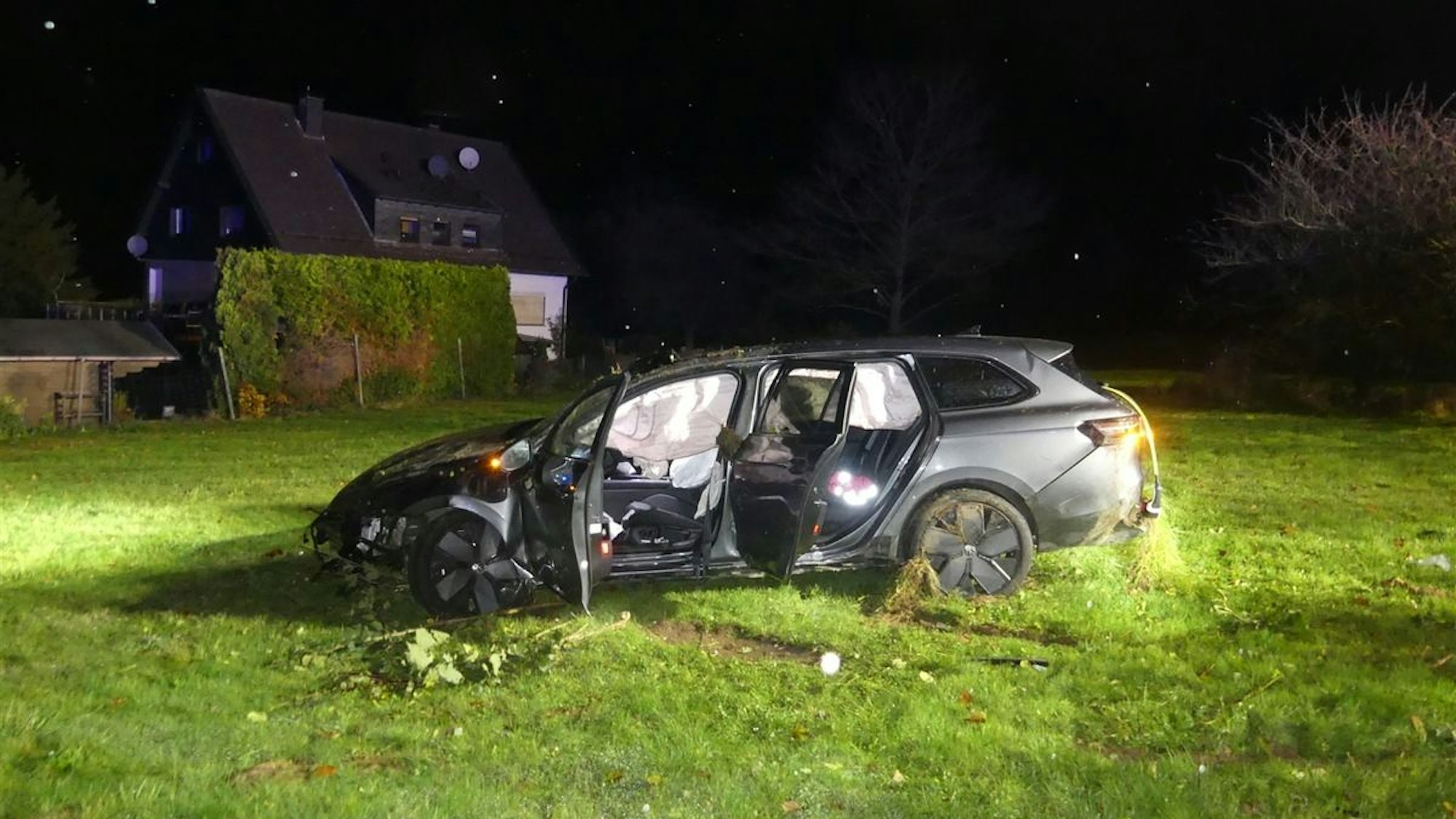 Ein auf dem Dach liegender, silberner VW auf einer Wiese.