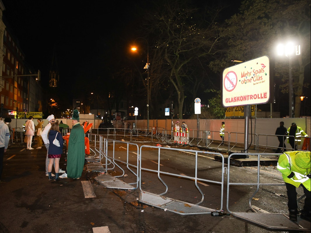 Ein paar verkleidete Menschen stehen an Absperrgittern.