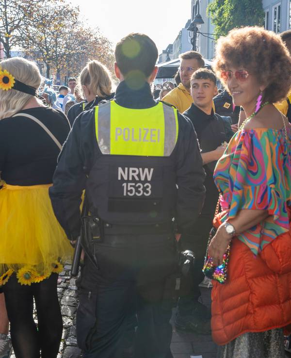 Ein Polizist bahnt sich den Weg durch verkleidete Menschen.
