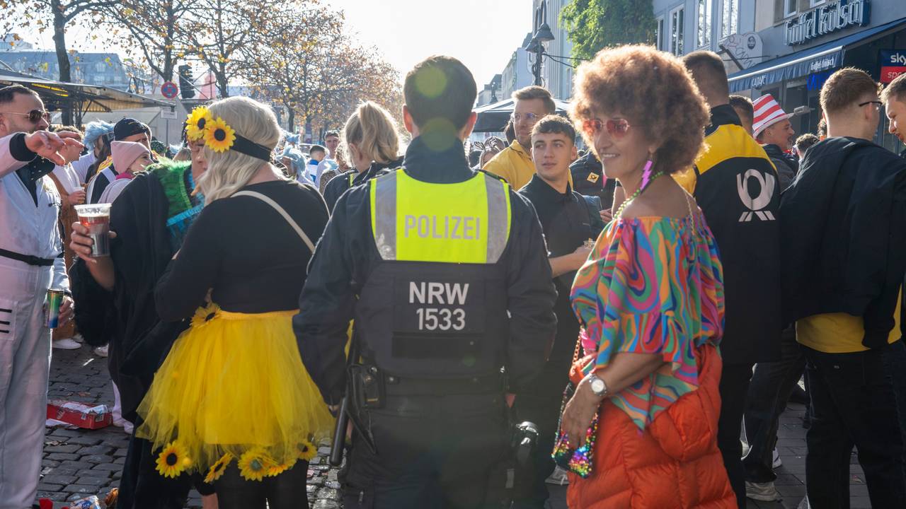 Ein Polizist bahnt sich den Weg durch verkleidete Menschen.