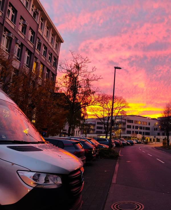 Der Himmel zwischen mehreren Häusern leuchtet in grellen Farben.