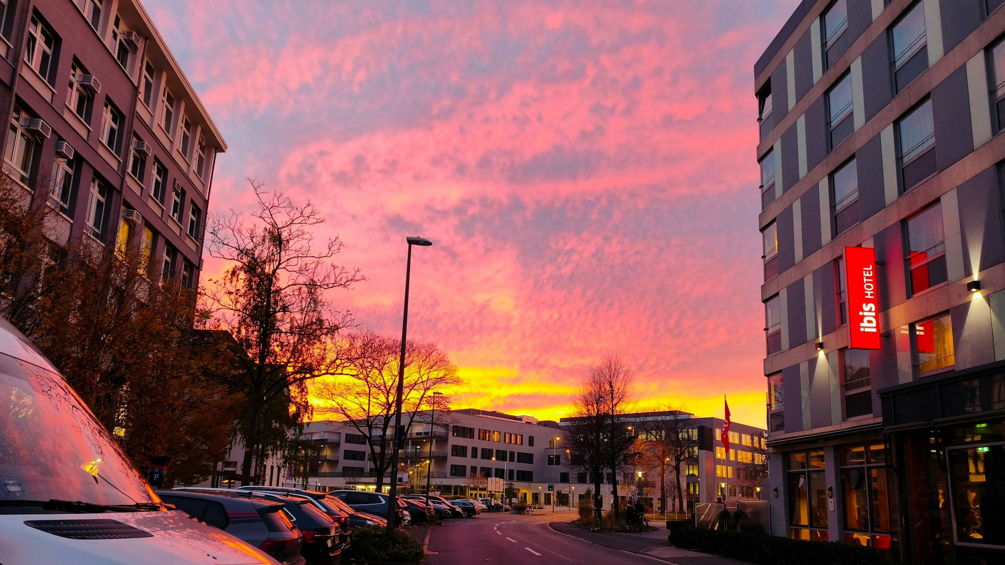 Der Himmel zwischen mehreren Häusern leuchtet in grellen Farben.