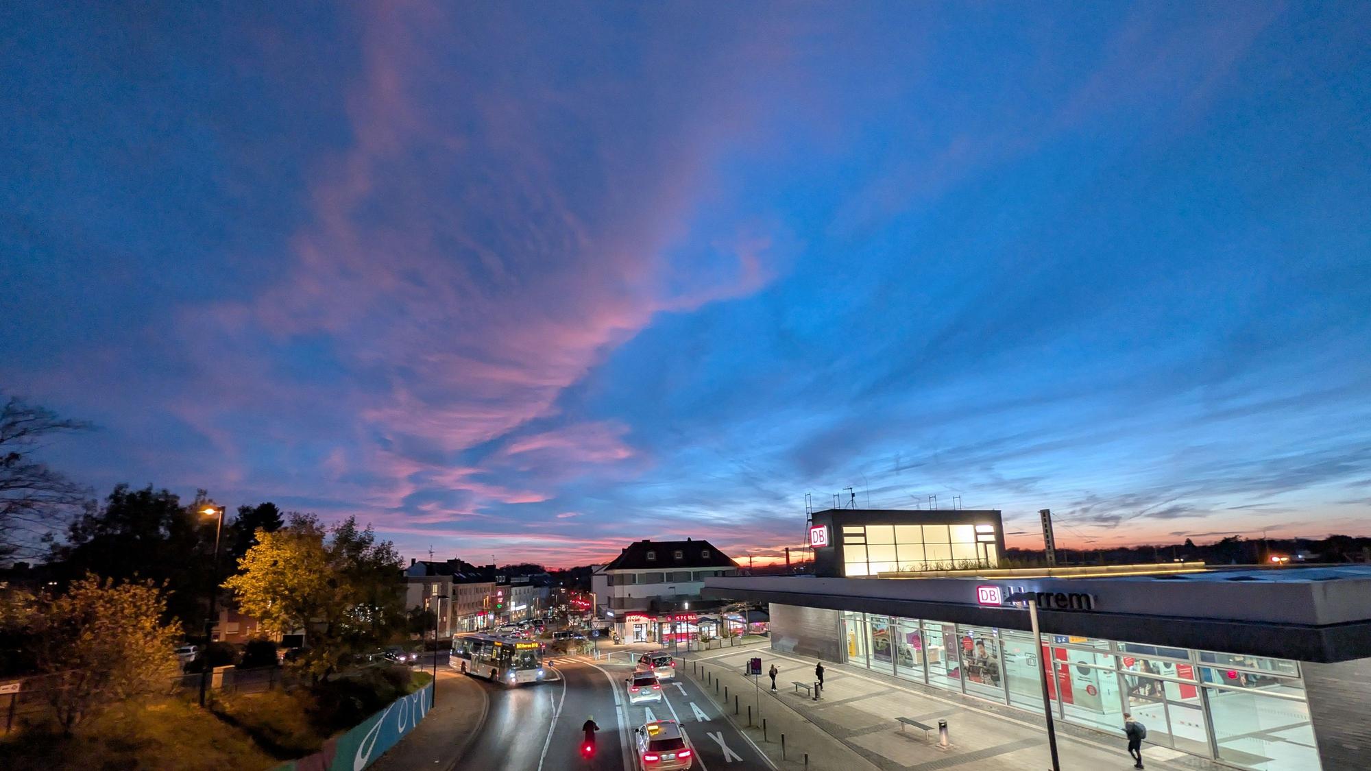 Über einem Bahnhof ist der Himmel in Blau und Pink gefärbt.