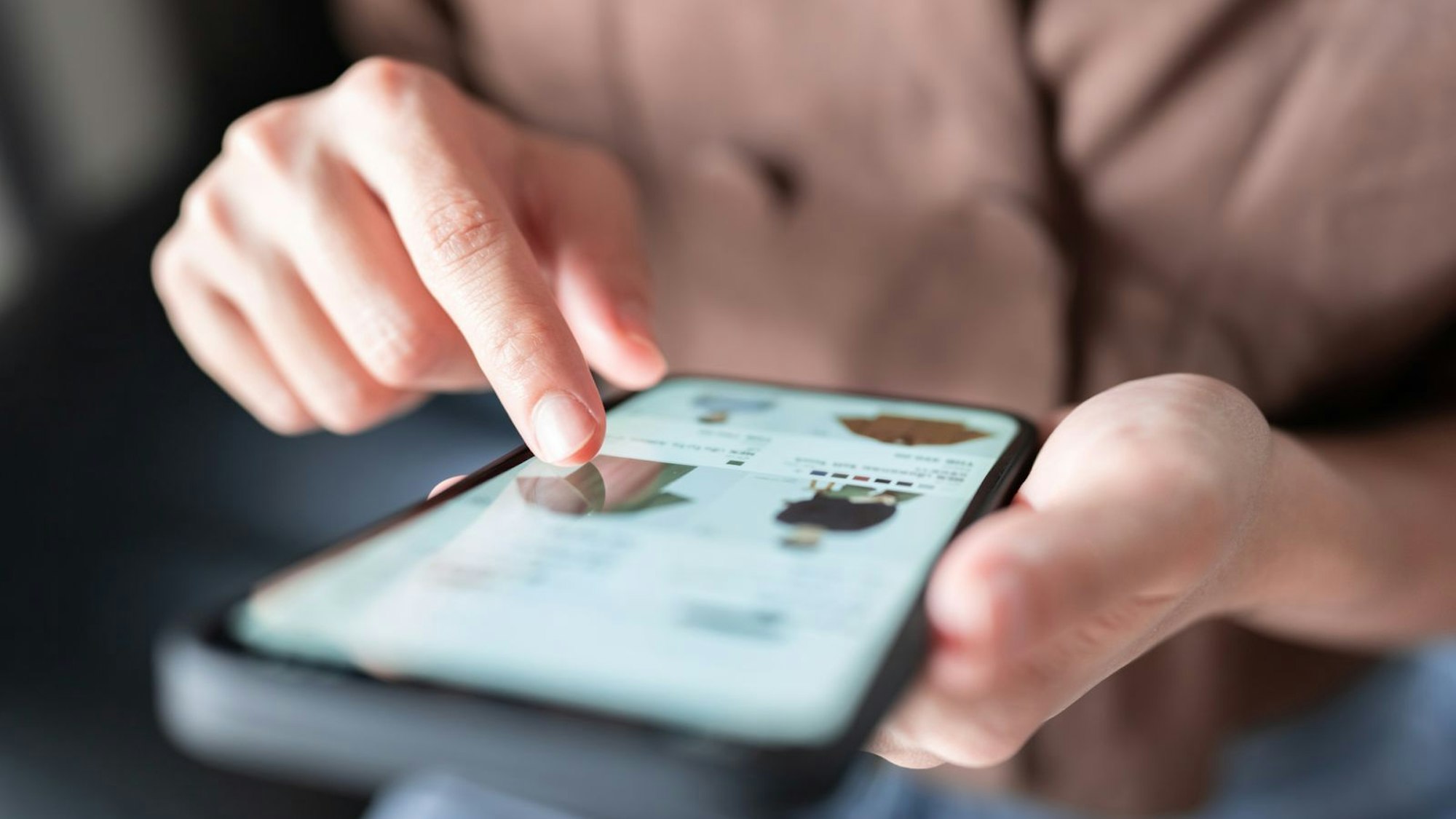 Eine Person guckt auf einem Handy nach Kleidung.