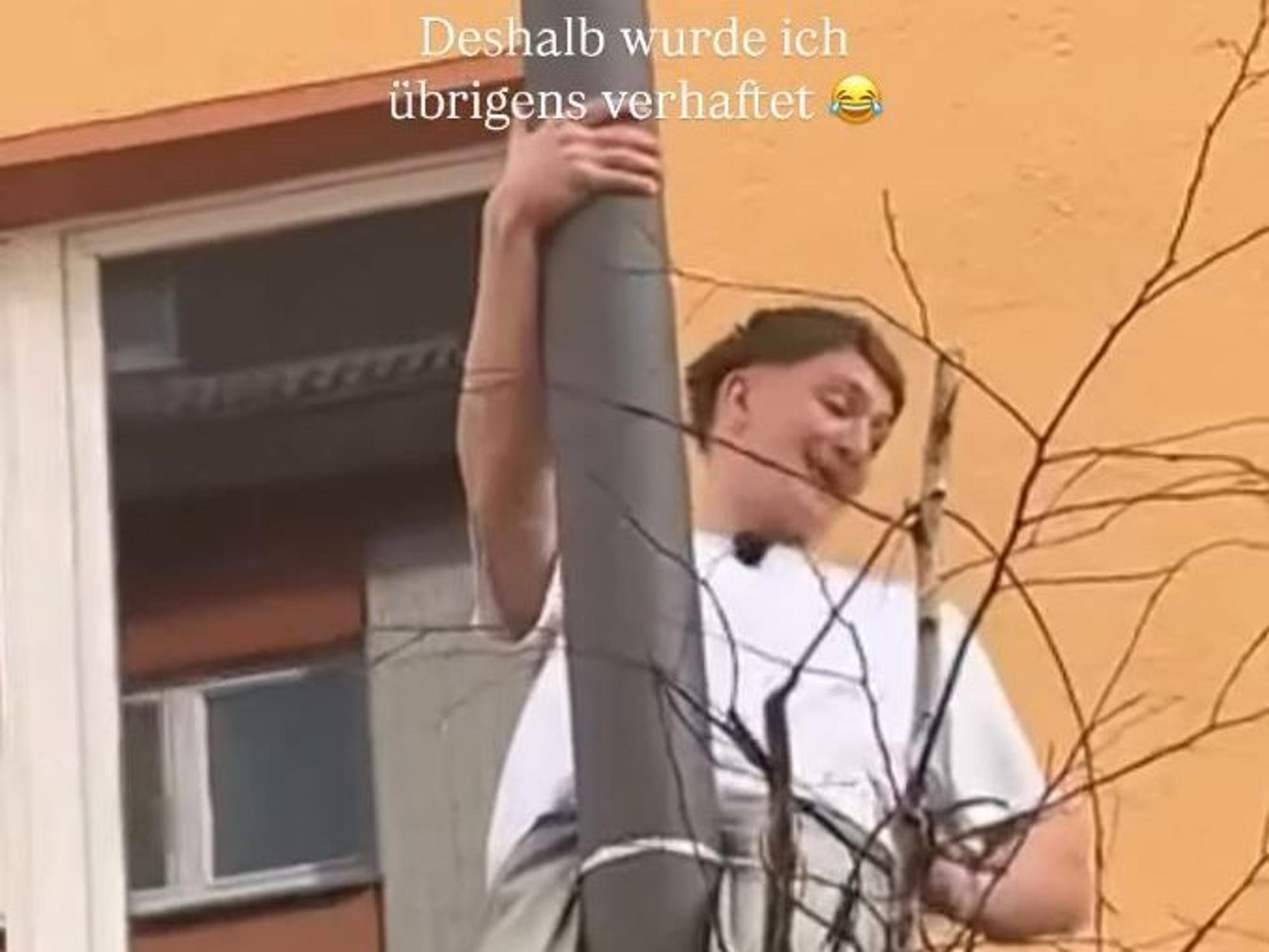 Ein Mann hängt an einem Laternmast.