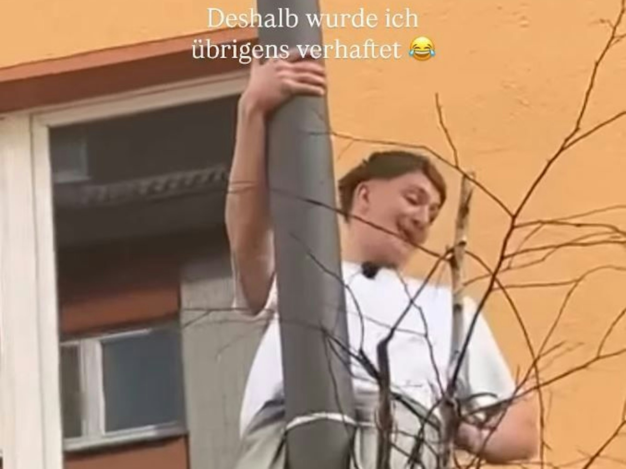 Ein Mann hängt an einem Laternmast.