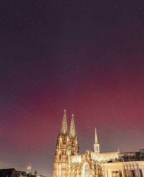 Der Kölner Dom ist beleuchtet, darüber ein farbiger Himmel.