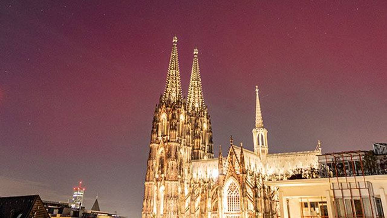 Der Kölner Dom ist beleuchtet, darüber ein farbiger Himmel.