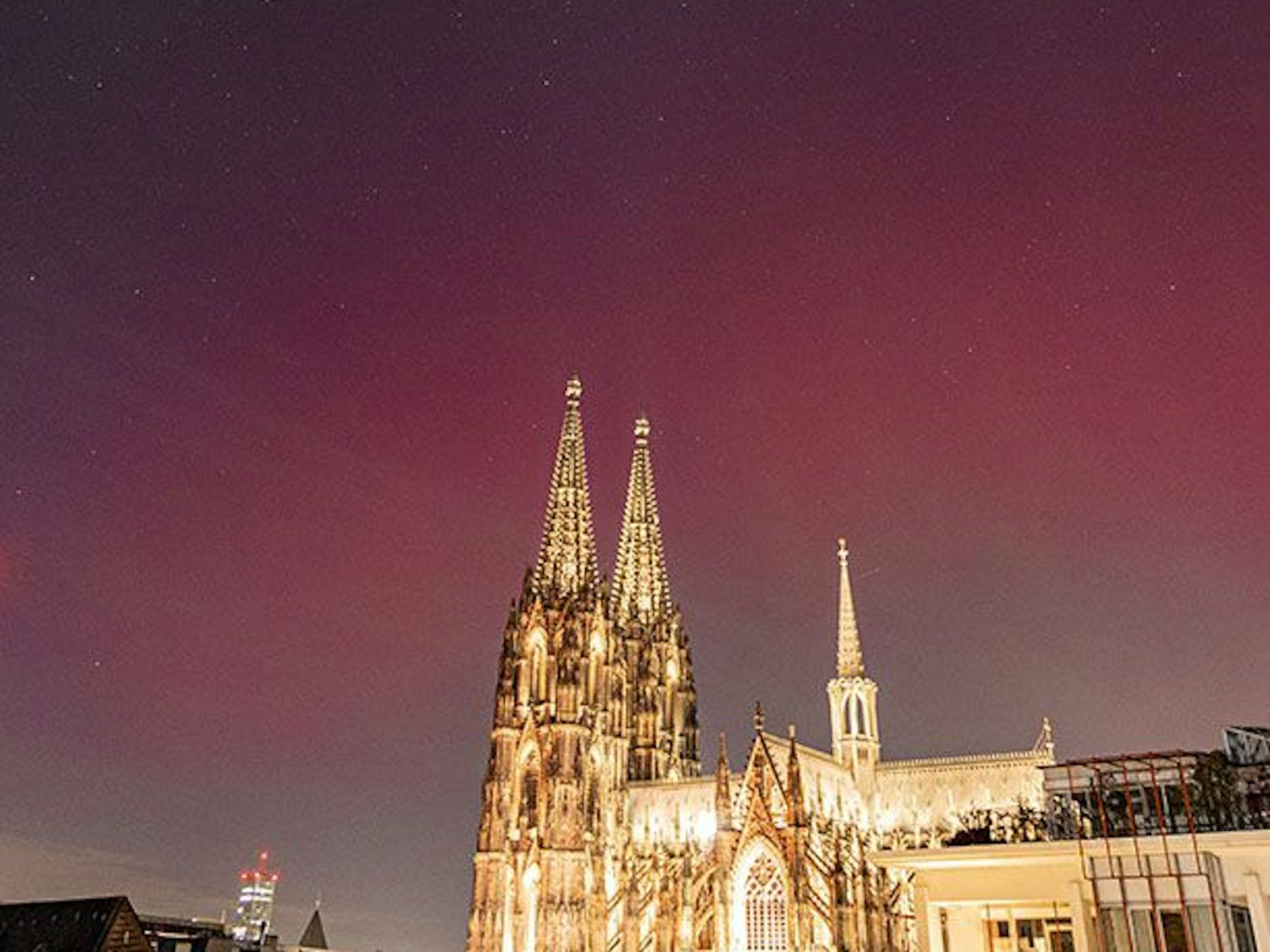 Der Kölner Dom ist beleuchtet, darüber ein farbiger Himmel.