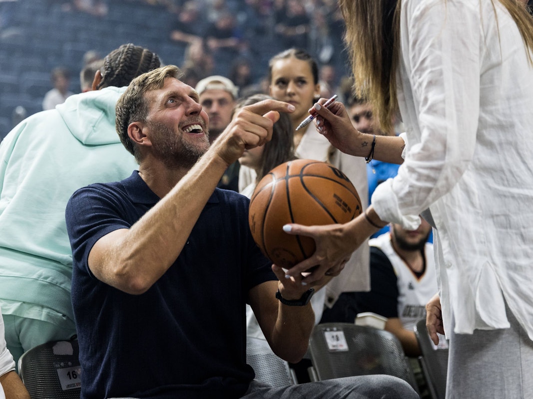 Dirk Nowitzki, ehemaliger deutscher Basketballer, gibt lachend Autogramme.
