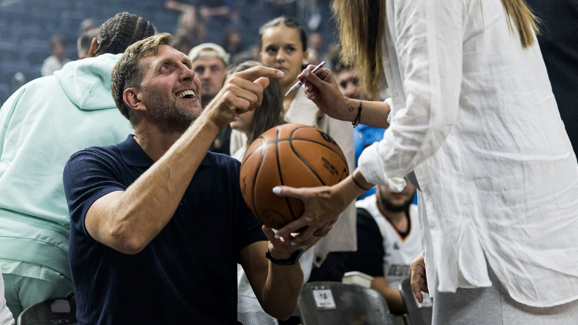 Dirk Nowitzki, ehemaliger deutscher Basketballer, gibt lachend Autogramme.