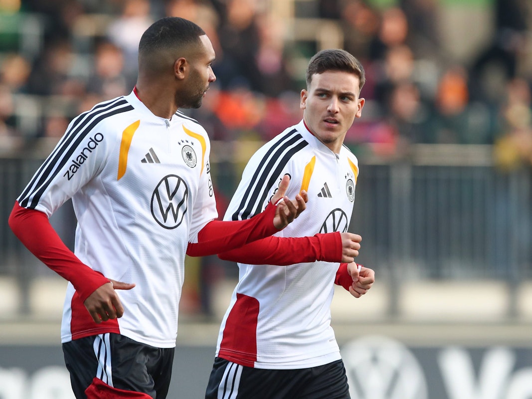 Jonathan Tah und Said El Mala unterhalten sich, während sie im Training laufen.