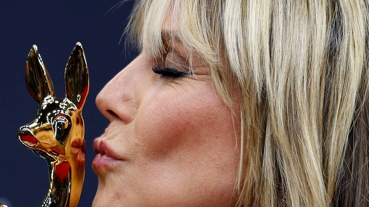 Eine Frau küsst eine Statue in Form eines Rehkitzes.