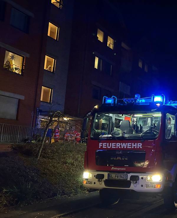 Feuerwehrfahrzeuge mit Blaulicht stehen vor einem Mehrfamilienhaus an der Gartenstraße in Rösrath-Hoffnungsthal.