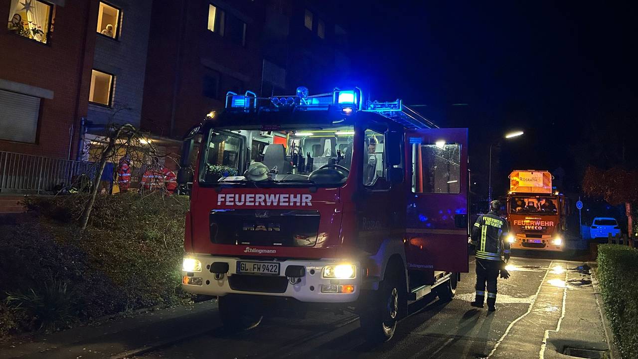 Feuerwehrfahrzeuge mit Blaulicht stehen vor einem Mehrfamilienhaus an der Gartenstraße in Rösrath-Hoffnungsthal.