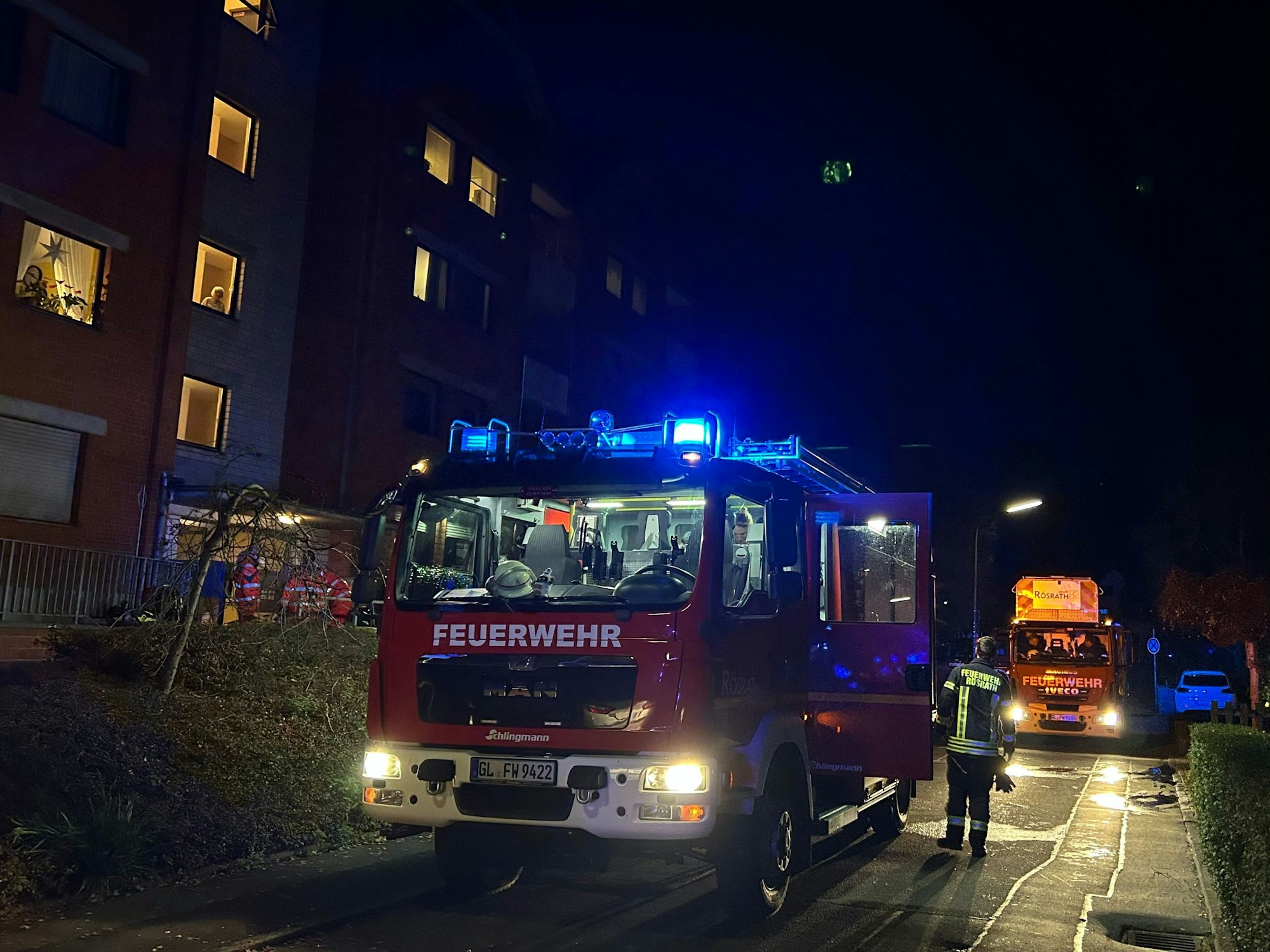 Feuerwehrfahrzeuge mit Blaulicht stehen vor einem Mehrfamilienhaus an der Gartenstraße in Rösrath-Hoffnungsthal.