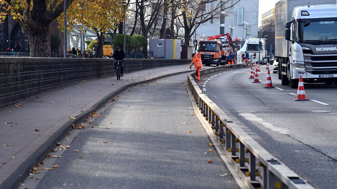 Arbeiter bauen einen Radweg auf einer Straße ab.
