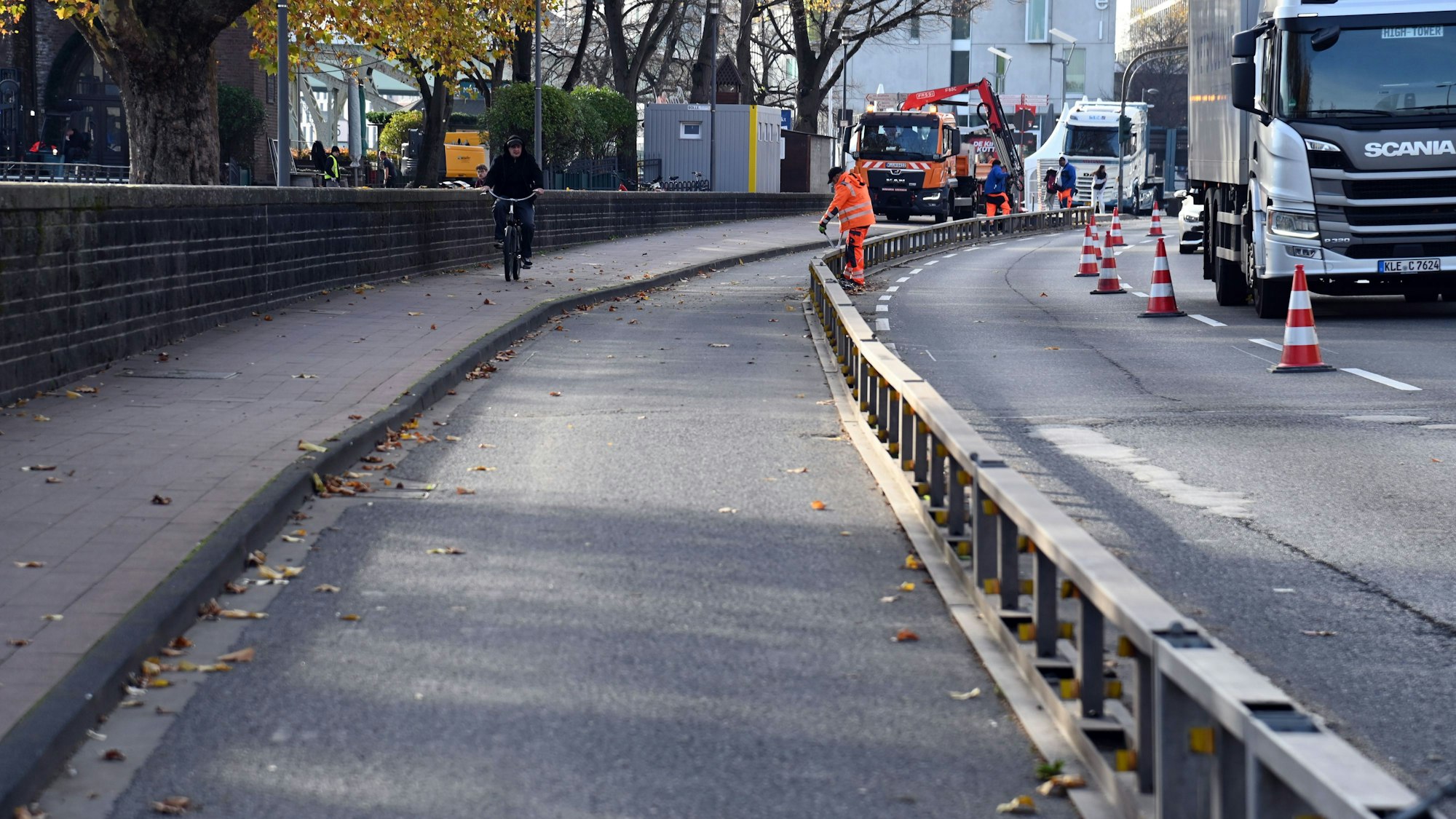 Arbeiter bauen einen Radweg auf einer Straße ab.