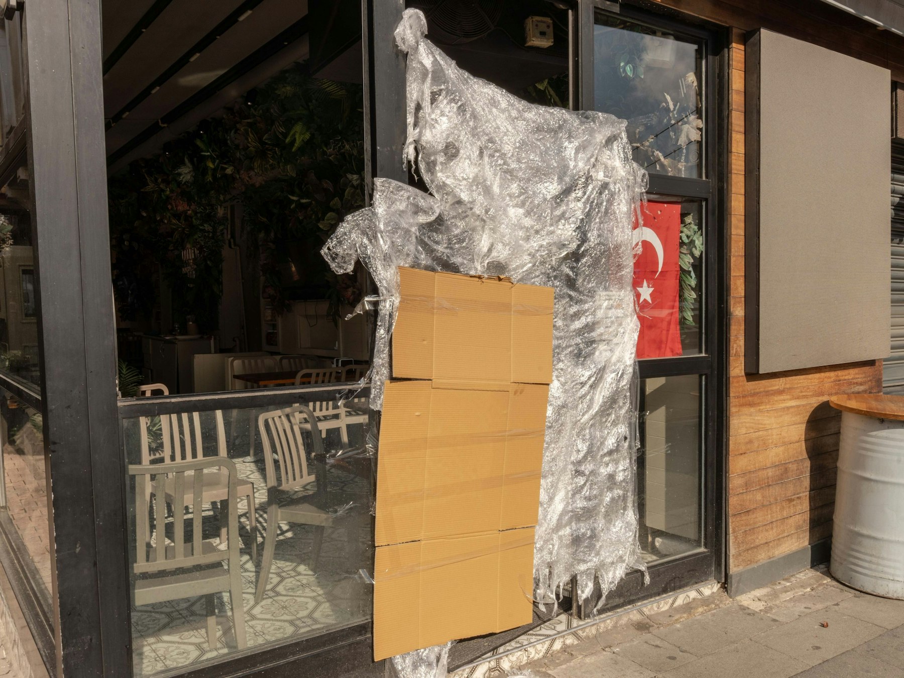 An einem türkischen Stand für Streetfood, der von den türkischen Behörden geschlossen wurde, hängen eine Pappe und eine Plastikplane neben einer türkischen Fahne.
