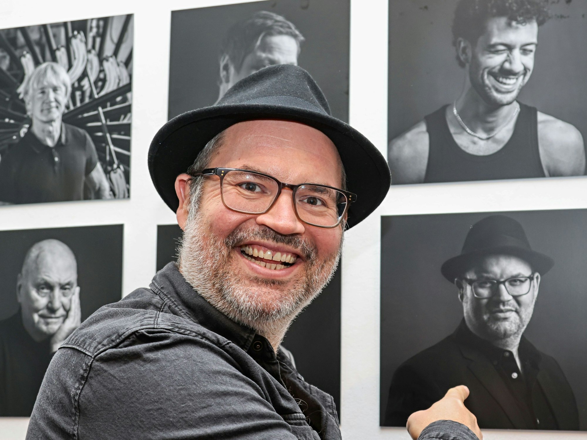 Björn Heuser zeigt auf sein Portraitfoto.