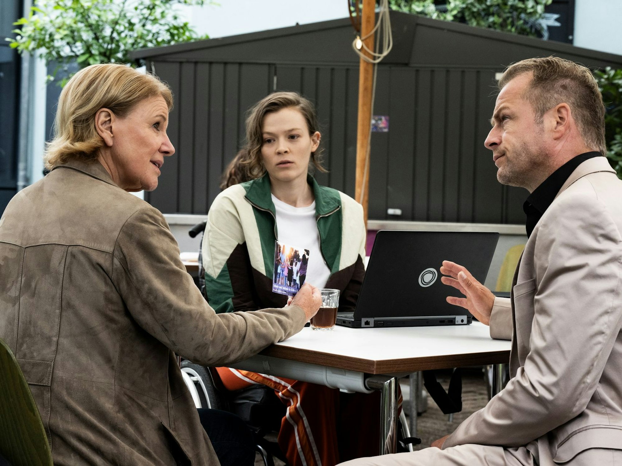 Zwei Frauen und ein Mann sitzen an einem Tisch und diskutieren.