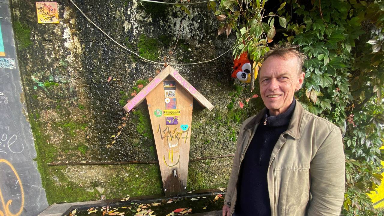 Schreiner Michael Krings steht vor einem alpin gestalteten Brunnen an der einer Brückenmauer