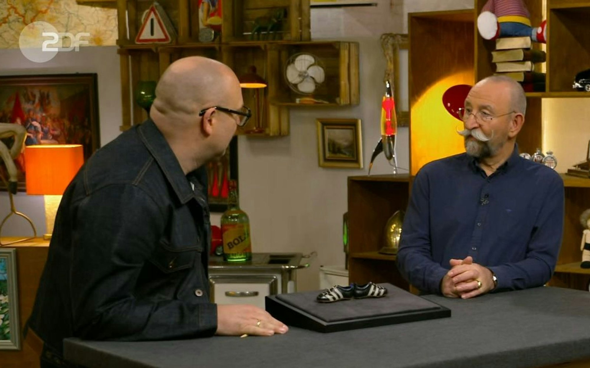 Da ist „Bares für Rares“-Experte Sven Deutschmanek einfach nur baff: In der Freitagsausgabe von „Bares für Rares“ offenbarte Horst Lichter eine mehr als überraschende Wissenslücke. Auslöser waren ein Fanrtikel von der WM 1966. (Bild: ZDF)