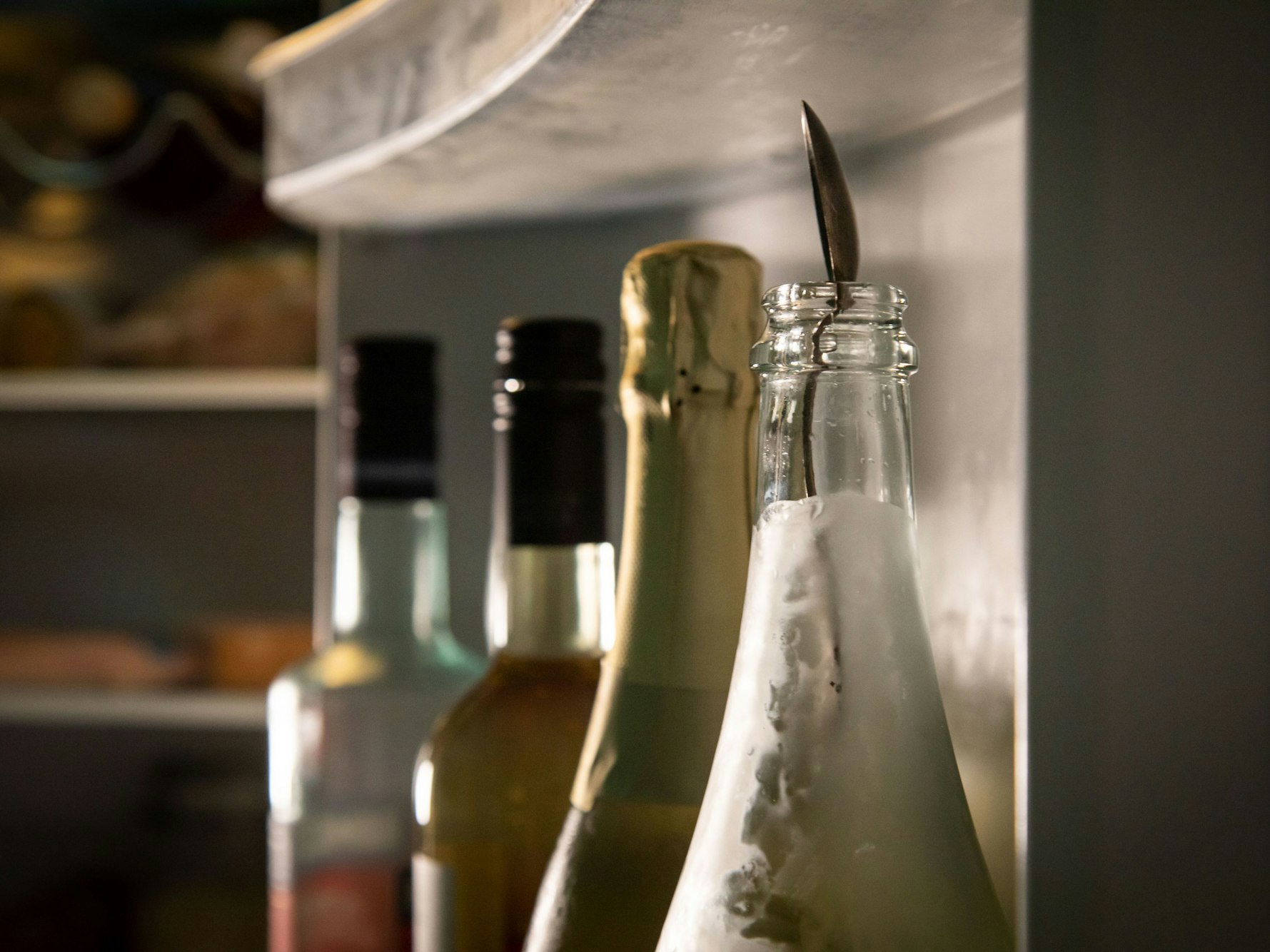 Ein Silberlöffel steckt im Hals einer geöffneten Sektflasche