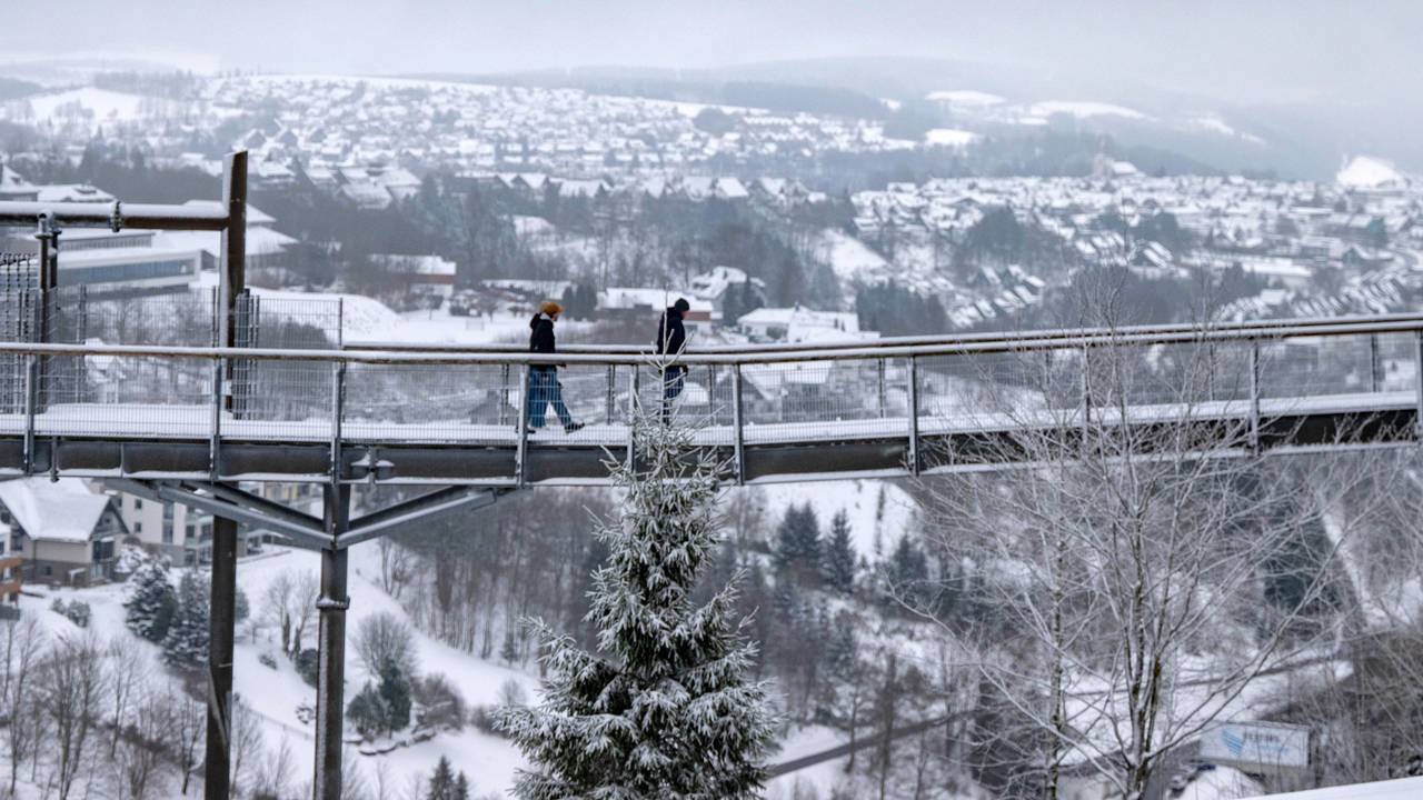 Spaziergänger gingen im Januar 2025 über den Skywalk neben der Bobbahn in Winterberg mit Blick auf die Landschaft im Schnee.