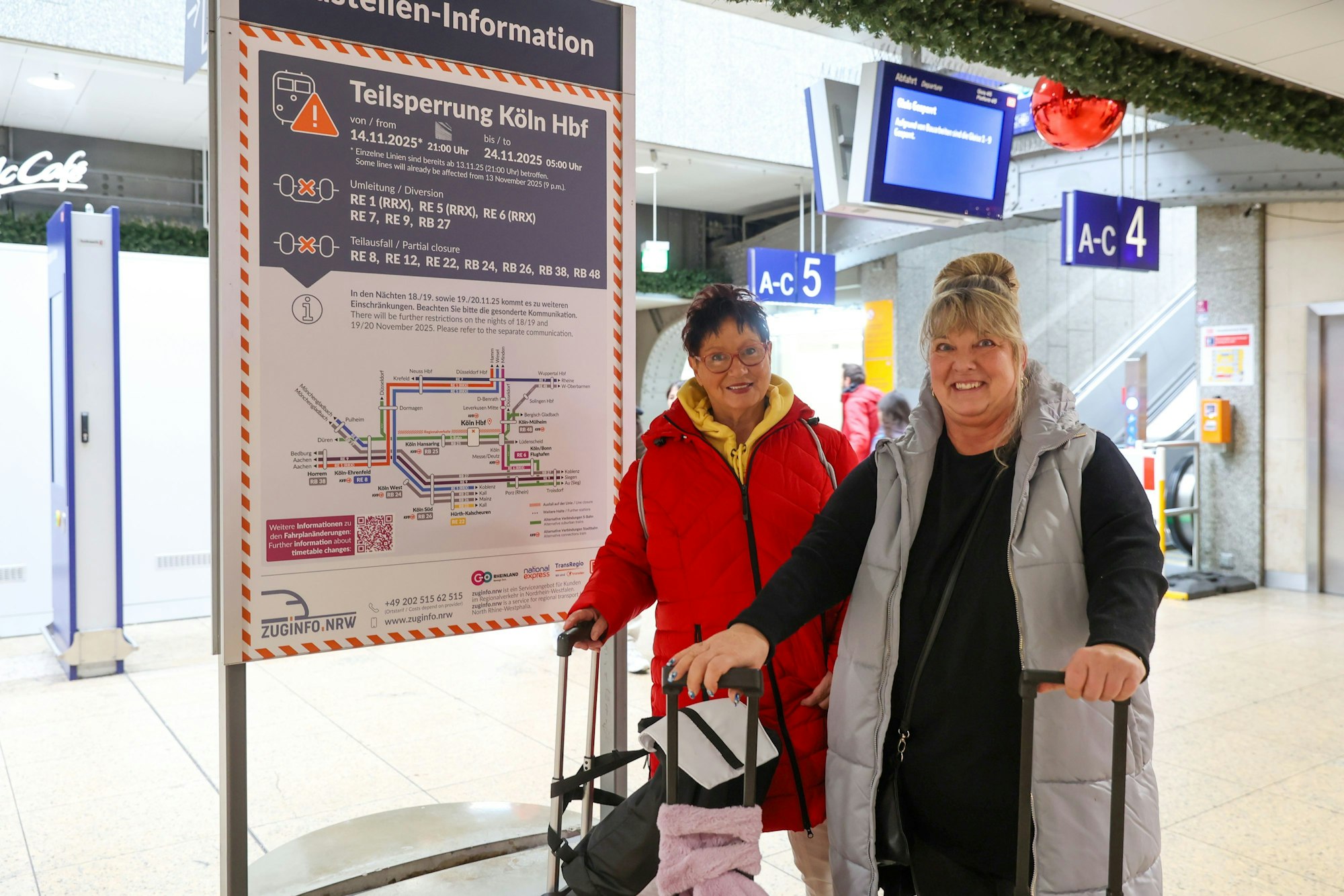 Zwei Frauen stehen mit Koffern im Hauptbahnhof.